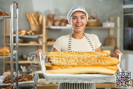 Young woman are standing in kitchen with basket of finished products baguettes