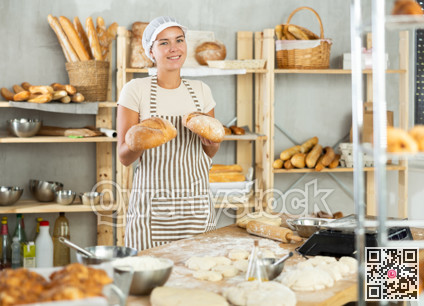 Enthusiastic young female baker presenting golden freshly baked bread