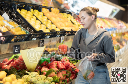 Young woman chooses peppers in store