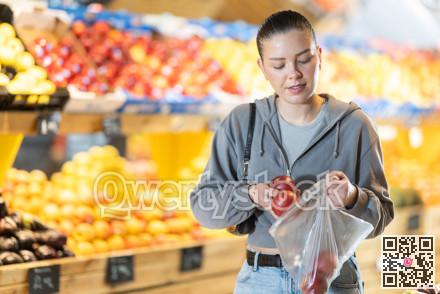 Young woman choosing apples in vegetable shop
