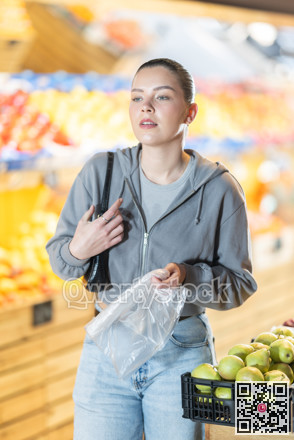 Young woman choosing eggplants at vegetable shop