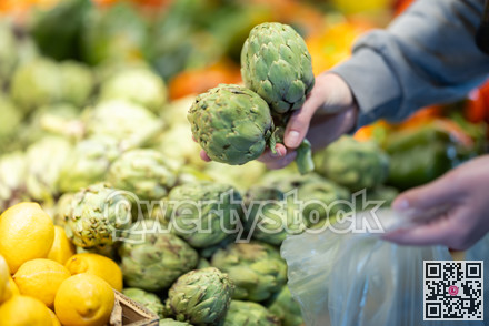 Shopper selects ripe artichokes at grocery supermarket closeup