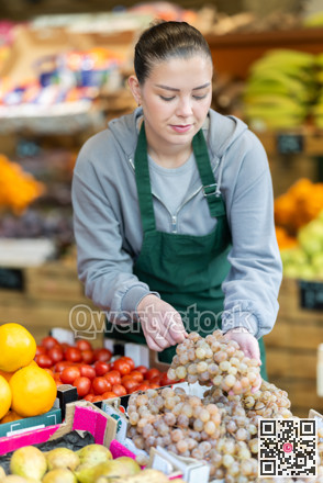 Female seller places ripe grape on display case