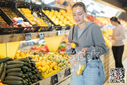 Young woman buyer choosing lemons at vegetable market