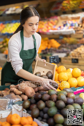 Young woman seller puts avocados in vegetable shop