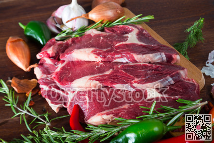 Raw beef steaks with rosemary and vegetables assortment on wooden desk