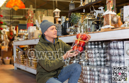Man choosing christmas balls in decorative goods store