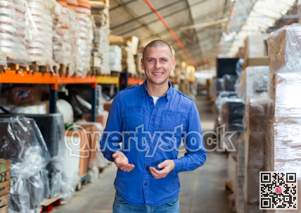 Warehouse worker standing among shelves and smiling