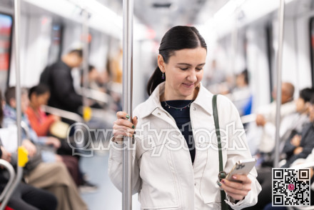 Woman using smartphone while traveling in subway car