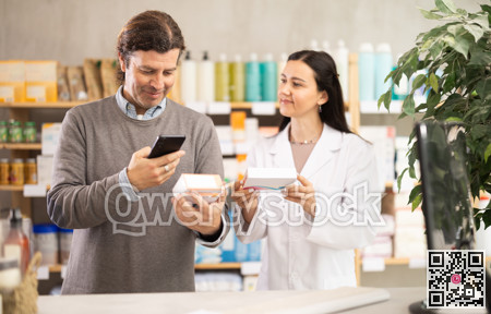 Middle-aged man scanning QR-code on pills box while pharmacist offering