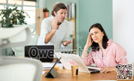 Adult man scolding adult female colleague working on laptop
