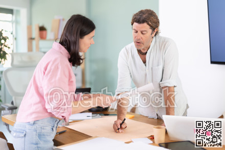 Man draws construction plan, woman gives document for review