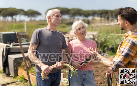 Elderly couple and young man talking together on farm field