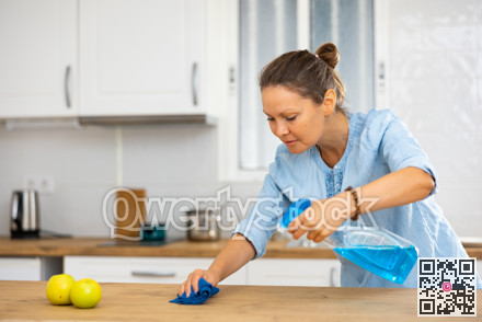 Focused woman cleaning kitchen table at home