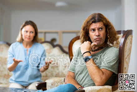 Middle-aged male and female settling relations between themselves sitting on the couch