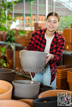 Young girl amateur gardener looking for flowerpots at garden market
