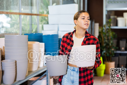 Young woman chooses flower pots for indoor plants
