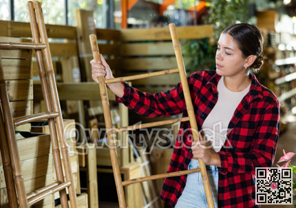 Young woman gardener is attentively examining a bamboo ladder