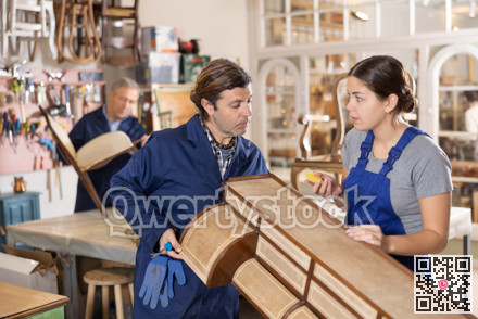 Male and female furniture makers working on vintage commode in workshop