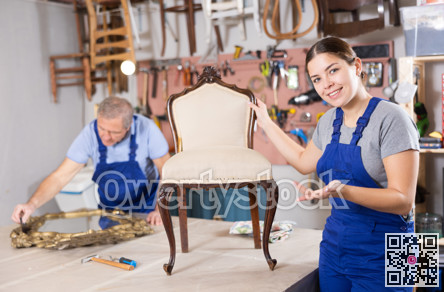 Female restorer demonstrating restored luxury chair in workshop