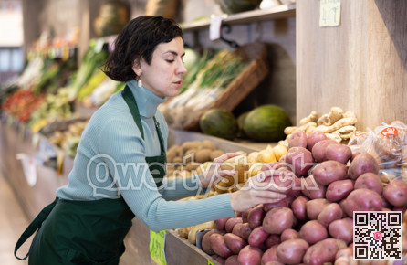 Adult woman seller puts potatoes on display