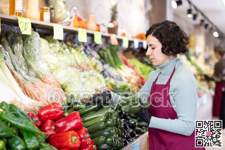 Woman shop seller puts zucchini goods on display case