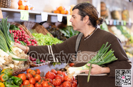 Male shopper choosing leek at supermarket counter