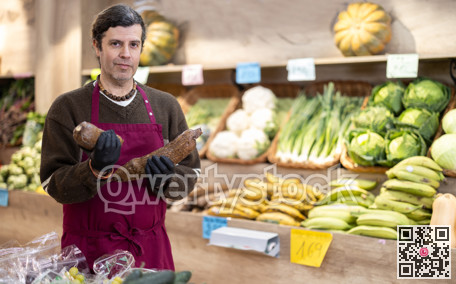 Adult man seller with cassava in vegetable shop