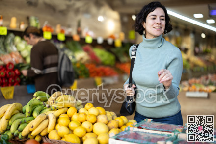 Adult woman choosing fruits and vegetables in vegetable shop