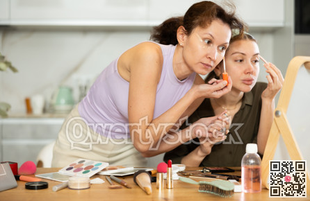 Two female friends applying makeup by vanity mirror at home