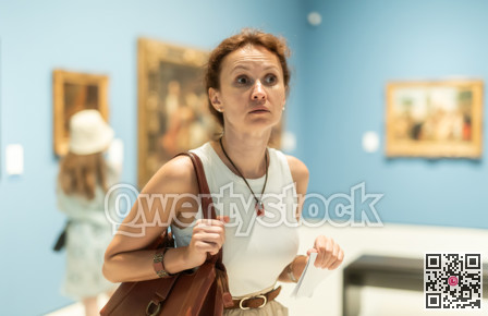 Thoughtful attentive woman standing in front of painting in art museum
