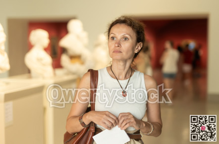 Woman looks at museum sculptures with brochure