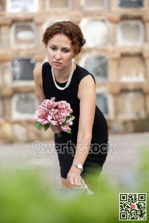 Woman in black dress came to cemetery to lay flowers on grave