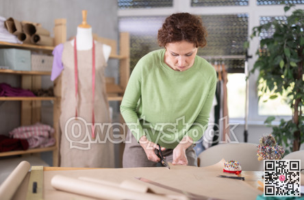 Woman tailor cuts out paper dress pattern