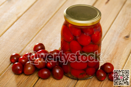 Glass jar with pickled tomatoes and fresh tomatoes