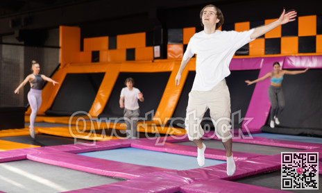Young guy trains jumping in trampoline center