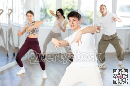Guy enjoys active dancing, learns new movements, moves synchronously with participants of lesson