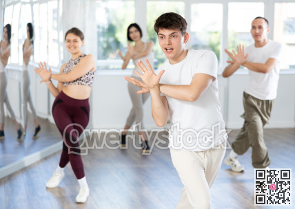 Guy with team of young like-minded people learn to dance modern dances