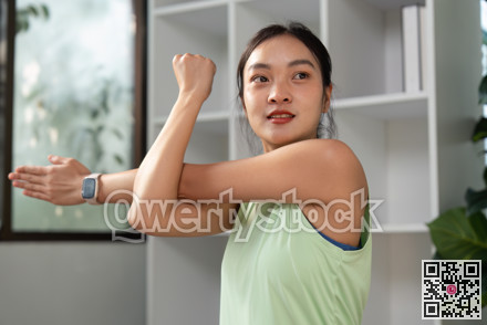 Fitness and Stretching. A woman engages in a stretching exercise at home, focusing on her arm and shoulder strength. photo 2409155