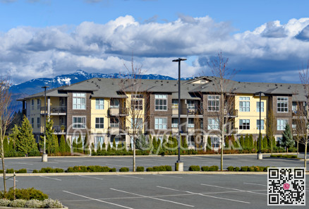 Low rise residential building with big parking lot in front on mountain background