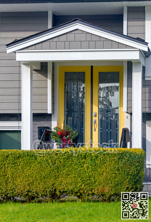 Yellow entrance door of residential house with green hedge row fence in front
