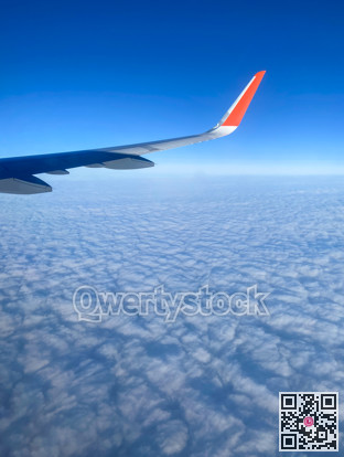 Wing of an air liner on blue sky and white clouds background